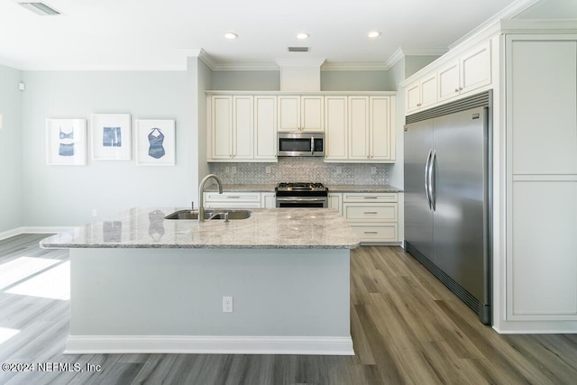 kitchen with backsplash, sink, appliances with stainless steel finishes, light stone counters, and wood-type flooring