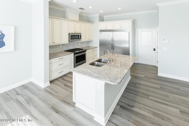 kitchen with a center island with sink, sink, light hardwood / wood-style flooring, light stone countertops, and appliances with stainless steel finishes