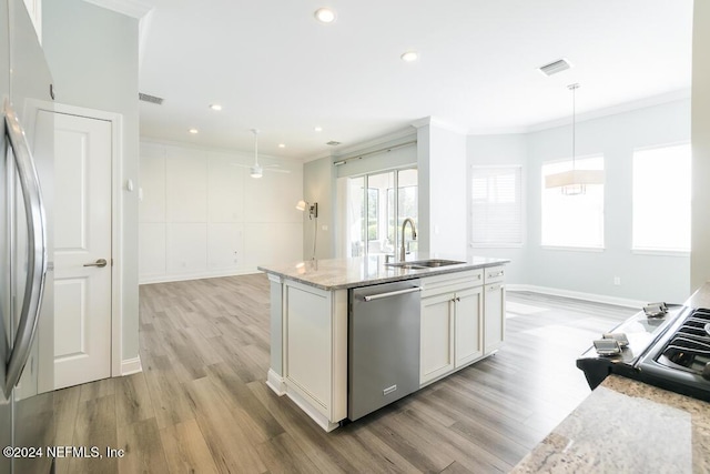 kitchen featuring appliances with stainless steel finishes, light wood-type flooring, light stone counters, sink, and hanging light fixtures