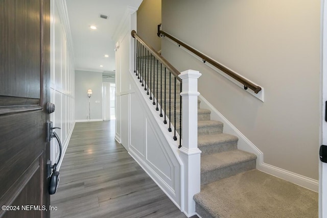 stairway with crown molding and hardwood / wood-style floors