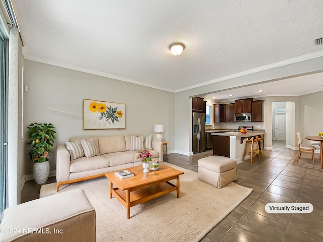 living room featuring a textured ceiling, dark tile patterned floors, and ornamental molding