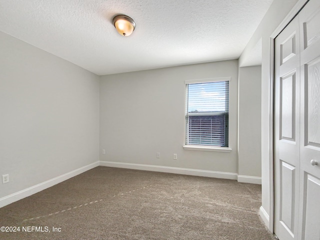 unfurnished bedroom featuring carpet, a textured ceiling, and a closet