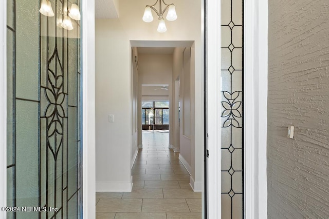 hall with a chandelier and light tile patterned floors