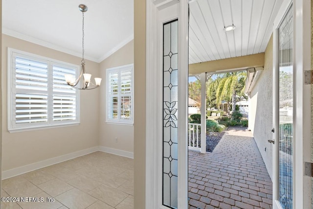 entryway featuring light tile patterned floors, an inviting chandelier, vaulted ceiling, and ornamental molding