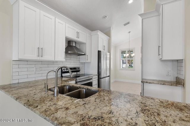 kitchen featuring white cabinets, appliances with stainless steel finishes, light stone counters, and wall chimney range hood