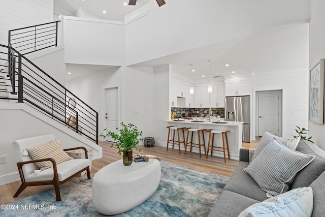 living room featuring a high ceiling, light hardwood / wood-style floors, and ceiling fan