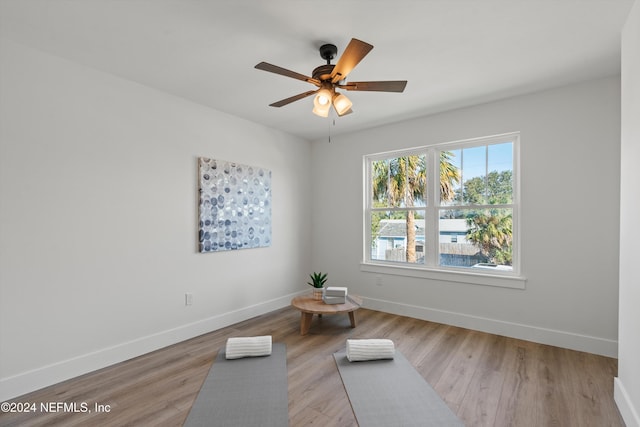 workout room with ceiling fan and light wood-type flooring