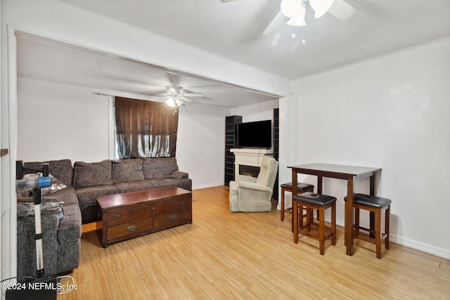 living room with light wood-type flooring, ceiling fan, and ornamental molding