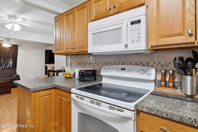 kitchen with kitchen peninsula, decorative backsplash, light hardwood / wood-style floors, and white appliances