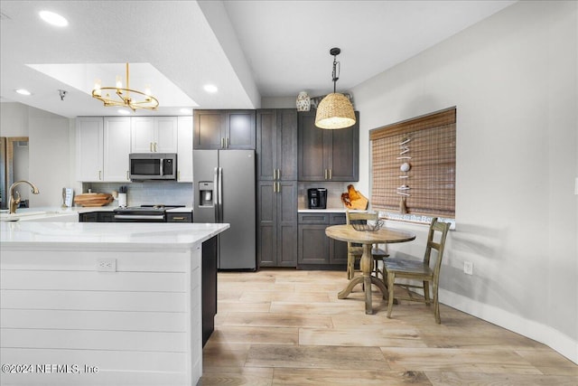 kitchen with sink, hanging light fixtures, stainless steel appliances, kitchen peninsula, and light hardwood / wood-style floors