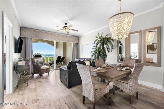 dining area featuring ceiling fan with notable chandelier, a textured ceiling, light wood-type flooring, and ornamental molding