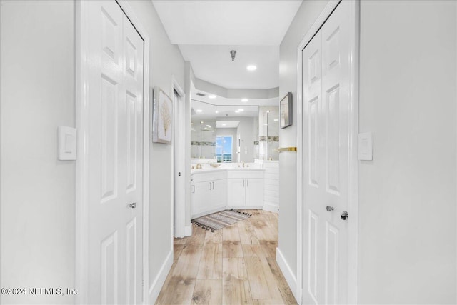 corridor featuring light wood-type flooring and sink