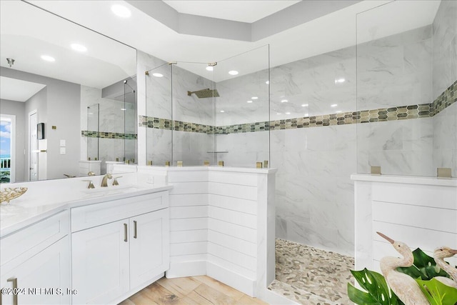 bathroom featuring a tile shower, vanity, and wood-type flooring