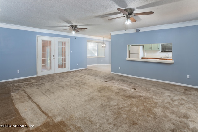 carpeted empty room featuring french doors, ceiling fan with notable chandelier, a textured ceiling, and ornamental molding