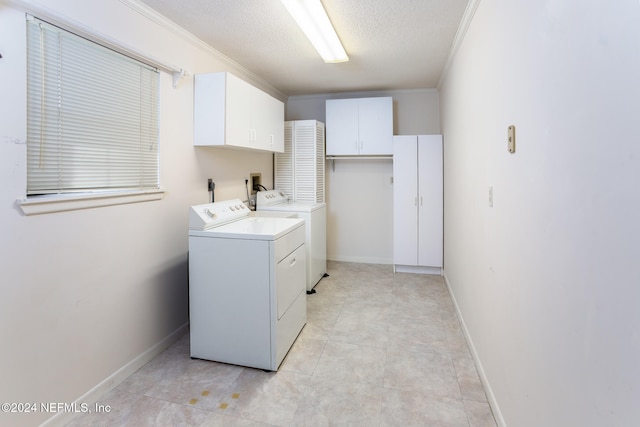 clothes washing area with cabinets, washing machine and dryer, crown molding, a textured ceiling, and light tile patterned floors