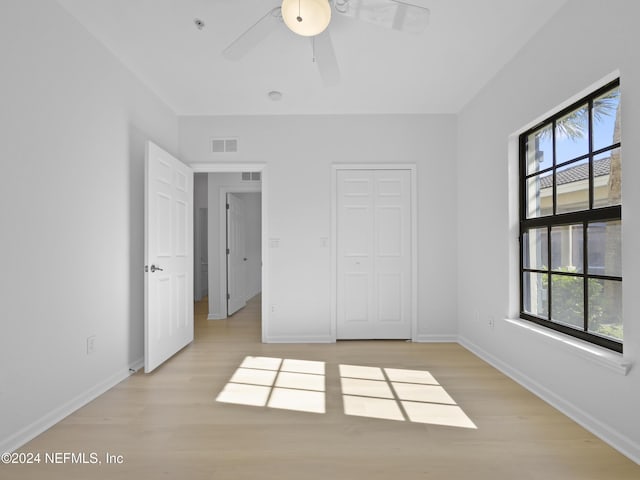 unfurnished bedroom featuring light wood-type flooring, a closet, multiple windows, and ceiling fan