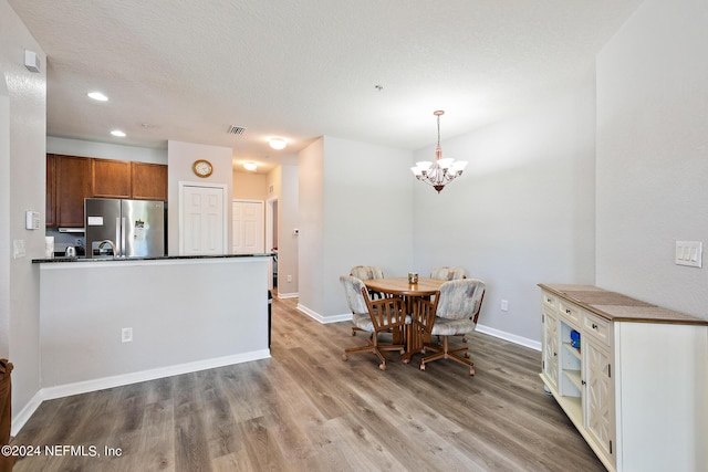 kitchen featuring stainless steel refrigerator, a chandelier, hanging light fixtures, and wood-type flooring