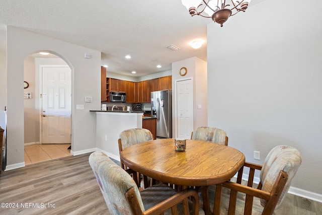 dining room with a notable chandelier, a textured ceiling, and light hardwood / wood-style flooring