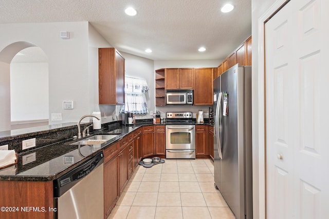 kitchen featuring dark stone countertops, sink, a textured ceiling, and appliances with stainless steel finishes