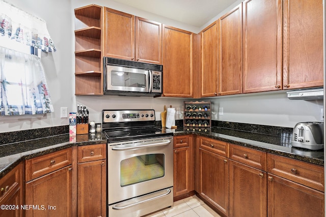 kitchen with appliances with stainless steel finishes, light tile patterned floors, and dark stone countertops