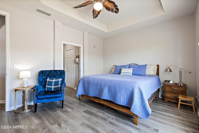 bedroom featuring a raised ceiling, ceiling fan, and wood-type flooring