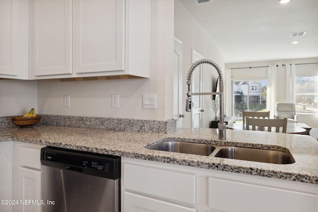 kitchen featuring light stone countertops, white cabinetry, stainless steel dishwasher, and sink