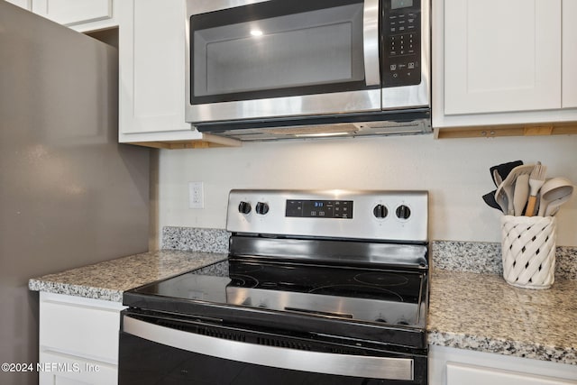 kitchen with white cabinets, appliances with stainless steel finishes, and light stone countertops