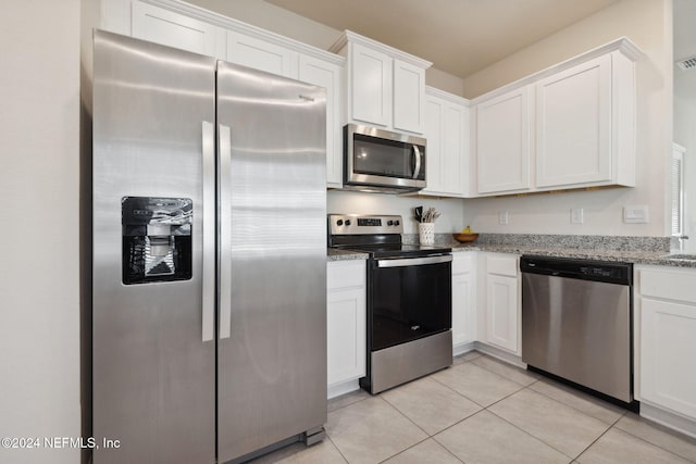 kitchen with light stone counters, white cabinets, and stainless steel appliances