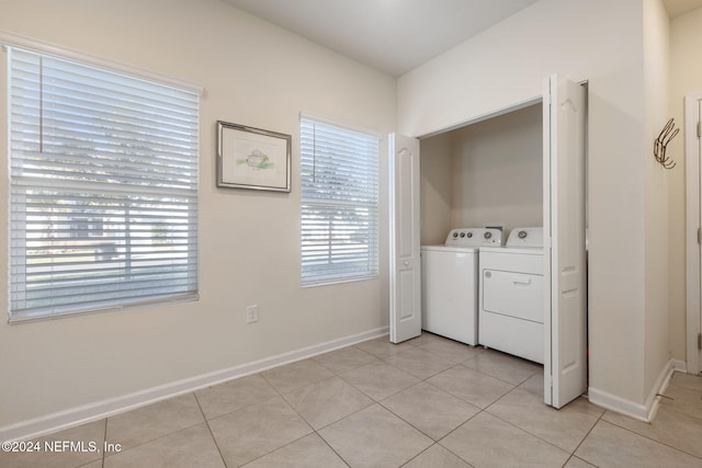 laundry room featuring washer and clothes dryer, light tile patterned floors, and a wealth of natural light