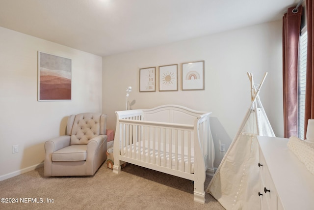 bedroom featuring light colored carpet and a nursery area