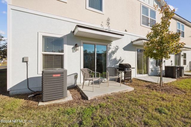 back of property featuring a lawn, central air condition unit, and a patio