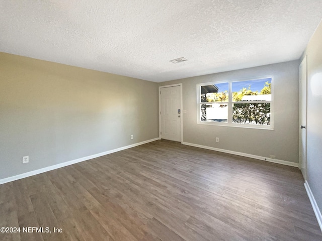 empty room featuring dark hardwood / wood-style floors and a textured ceiling