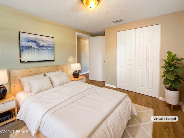 bedroom featuring hardwood / wood-style floors, a textured ceiling, and a closet