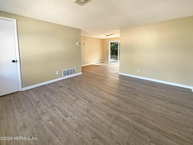 spare room featuring dark hardwood / wood-style flooring and a textured ceiling