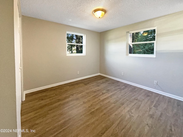 spare room featuring dark wood-type flooring and a textured ceiling