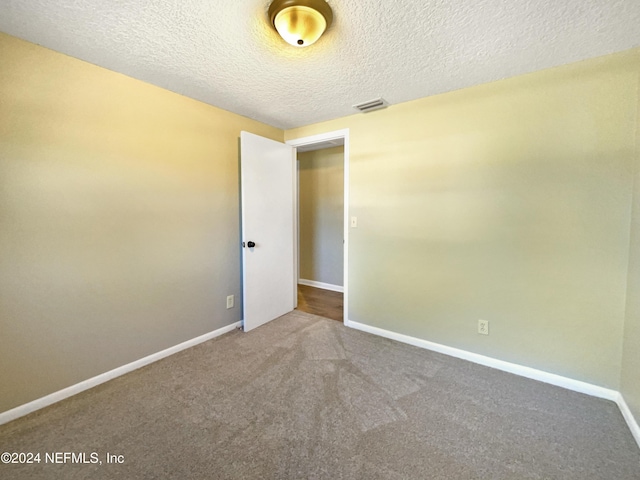 carpeted empty room with a textured ceiling