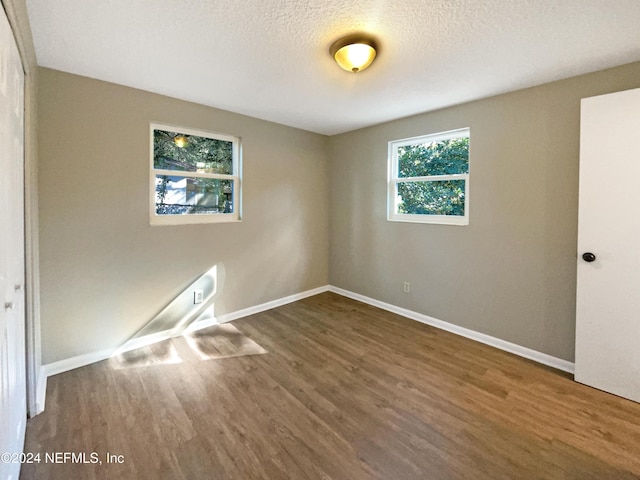 unfurnished room featuring dark hardwood / wood-style flooring and a textured ceiling