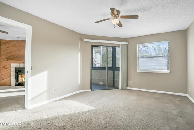 spare room with carpet flooring, a textured ceiling, ceiling fan, and wooden walls