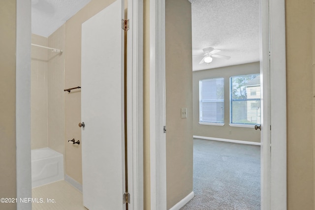 corridor featuring light carpet and a textured ceiling