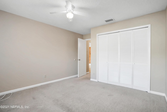 unfurnished bedroom featuring ceiling fan, light colored carpet, and a closet