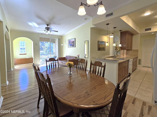 dining space featuring light wood-type flooring, ceiling fan, crown molding, and sink