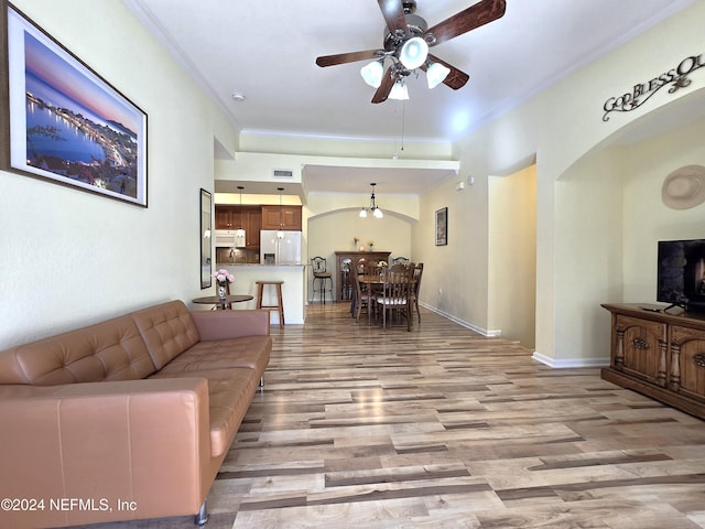 living room featuring ceiling fan, light wood-type flooring, and crown molding