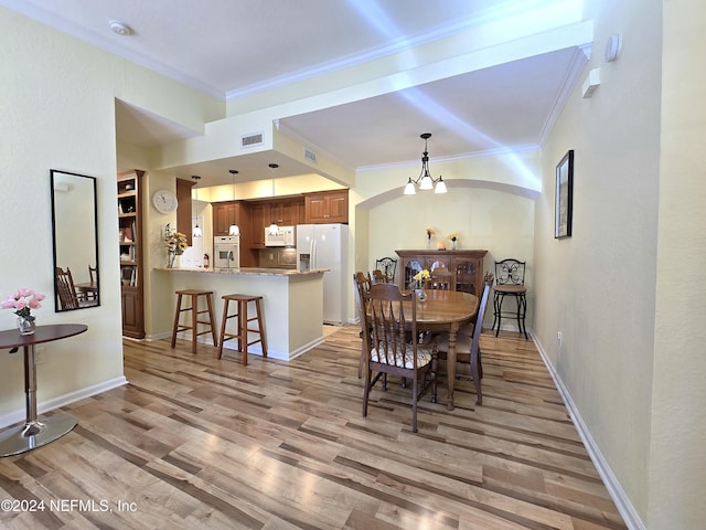 dining space with light hardwood / wood-style floors, ornamental molding, and a chandelier