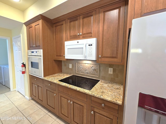 kitchen with tasteful backsplash, light stone counters, light tile patterned floors, and white appliances