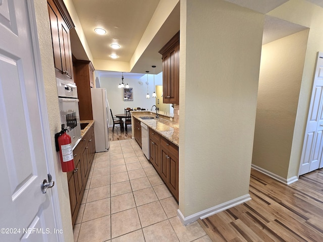 kitchen with light stone countertops, sink, an inviting chandelier, light hardwood / wood-style flooring, and decorative light fixtures