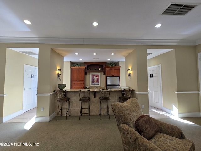 kitchen with kitchen peninsula, a kitchen breakfast bar, light colored carpet, and stainless steel refrigerator