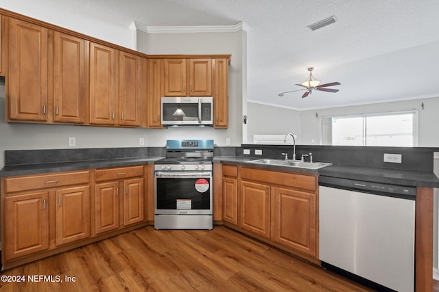 kitchen with hardwood / wood-style floors, crown molding, sink, and appliances with stainless steel finishes