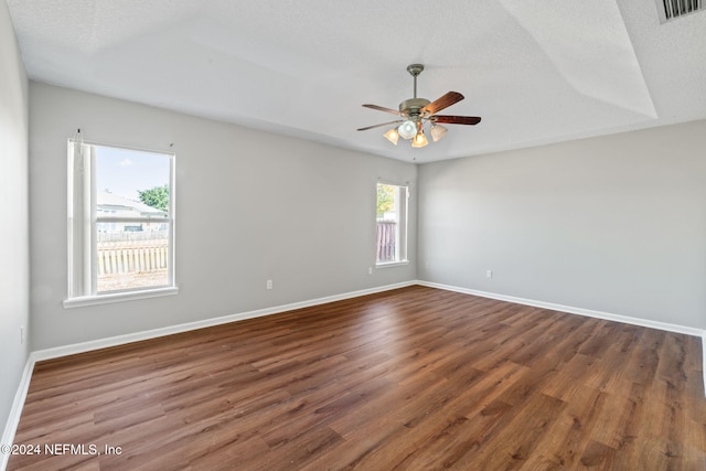 empty room with dark hardwood / wood-style floors, a textured ceiling, and a wealth of natural light