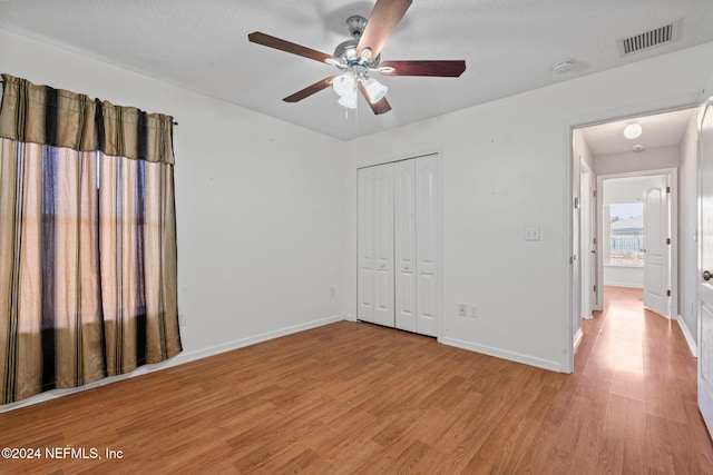 unfurnished bedroom with a closet, ceiling fan, light hardwood / wood-style flooring, and a textured ceiling