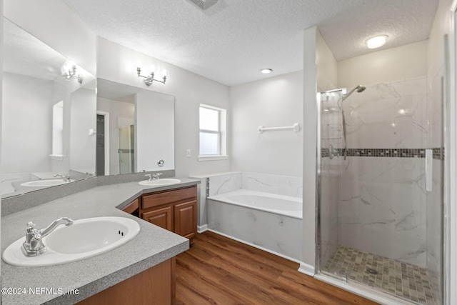 bathroom with separate shower and tub, hardwood / wood-style floors, vanity, and a textured ceiling